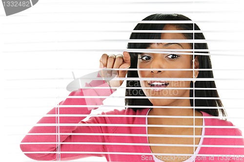 Image of Woman looking through venetian blinds