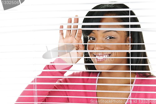 Image of Smiling woman looking through blinds