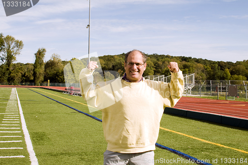 Image of middle age senior man stretching exercising on sports field