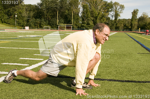 Image of   middle age senior man stretching exercising on sports field