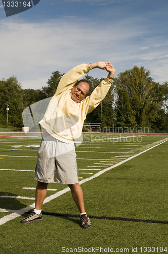 Image of middle age senior man stretching exercising on sports field