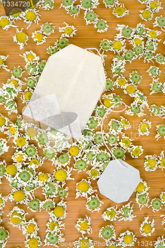 Image of Bag of chamomile tea with dry chamomilla flowers over wooden background