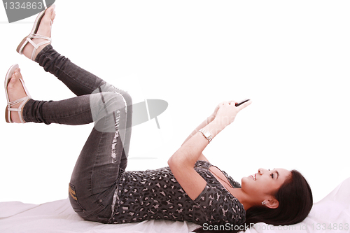 Image of beautiful young girl laying on a pillow chatting on a cell phone