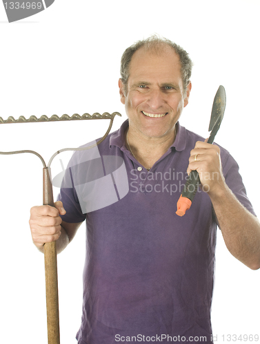 Image of middle age senior man gardener with spade and  bow rake tools