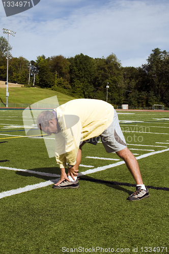 Image of middle age senior man stretching exercising on sports field