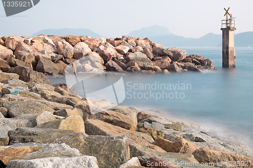 Image of Lighthouse on a Rocky Breakwall: A small lighthouse warns of a r