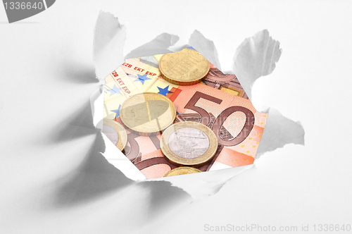 Image of euro money behind hole in paper