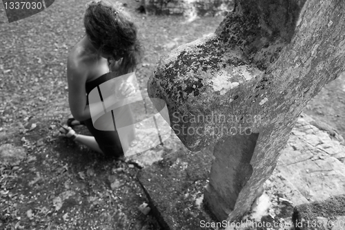 Image of Woman kneeling in front of a stone cross