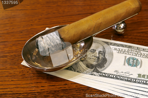 Image of Cigar on a stand with money