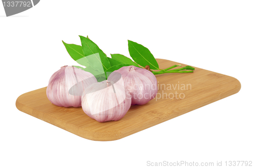 Image of Garlic on the board with a bay leaf.