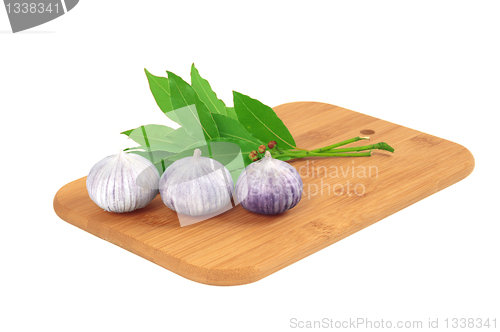 Image of Garlic on the board with a bay leaf.