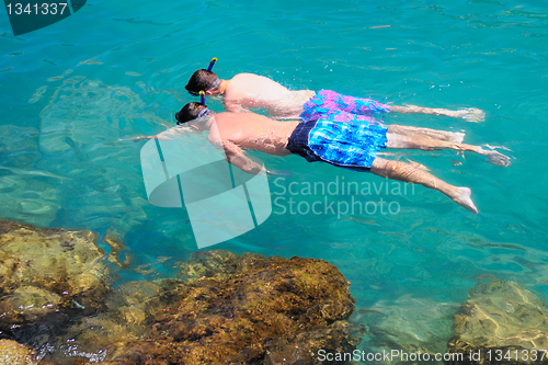 Image of Two tourists snorkeling in clear sea water.