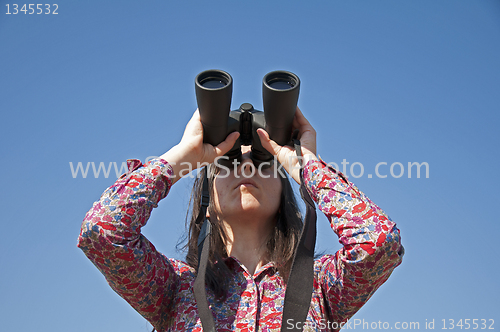 Image of Young woman using binoculars 