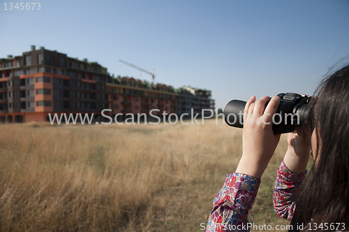 Image of Woman watching with binoculars building construction