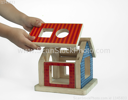 Image of Boy hands and wood colorful house toy 