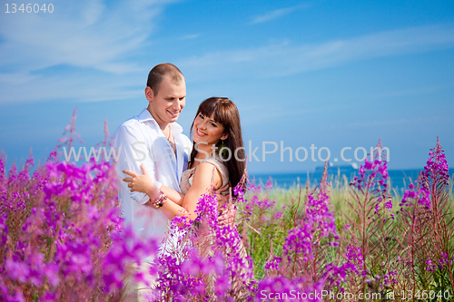 Image of Romantic couple among purple flowers near blue sea