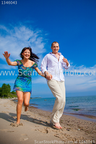 Image of Enamored couple running along the coast of sea