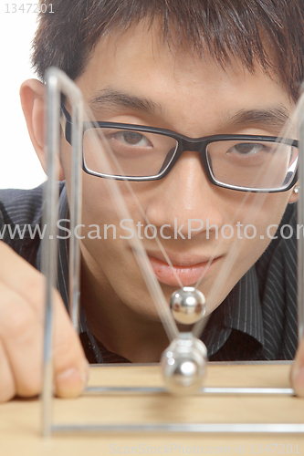 Image of man moving Newton balls in office 