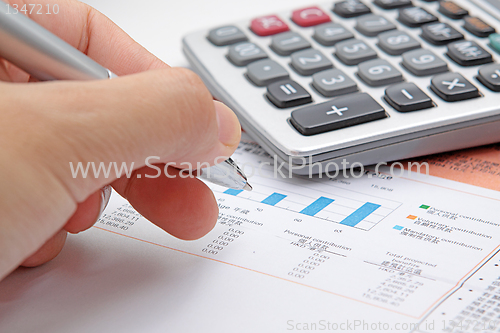 Image of Businessman's hand showing diagram on financial report with pen.
