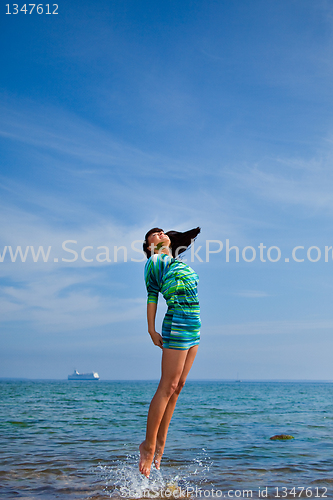 Image of beautiful girl jumping out of sea 