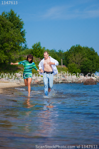 Image of Enamored couple running along the coast of sea