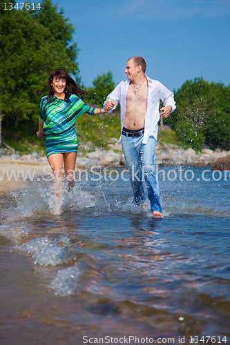 Image of Enamored couple running along the coast of sea