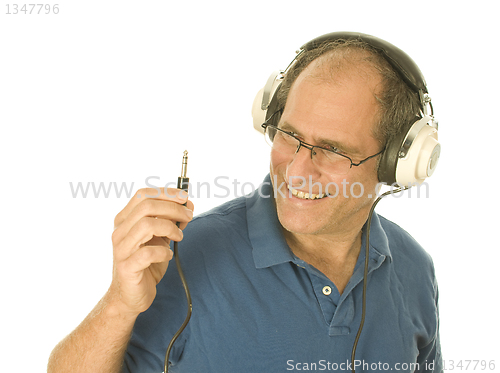 Image of senior man wearing music head phones looking at plug