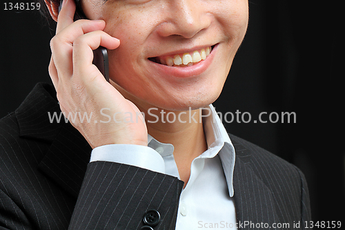 Image of portrait of e young man talking on mobile against a black backgr