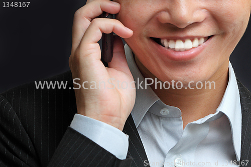 Image of portrait of e young man talking on mobile against a black backgr