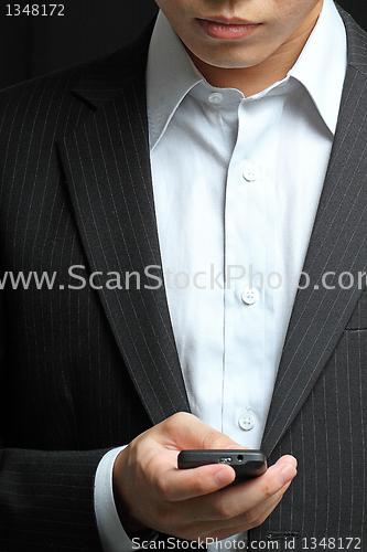 Image of business man in black suit working on pda or smartphone 