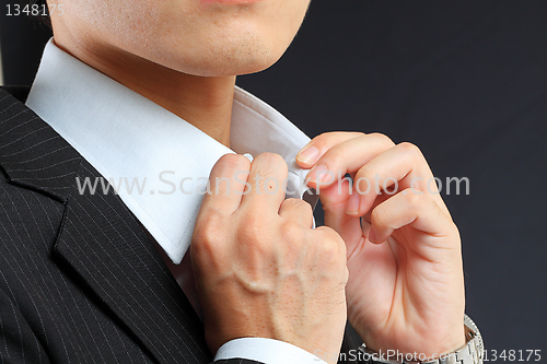 Image of young man adjusting his suit on a black background 