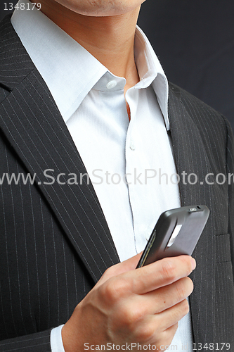 Image of business man in black suit working on pda or smartphone 