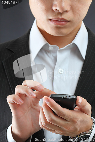 Image of business man in black suit working on pda or smartphone 