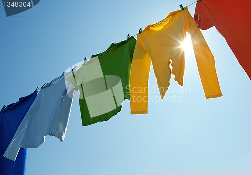 Image of Colorful clothes on a laundry line and sun shining