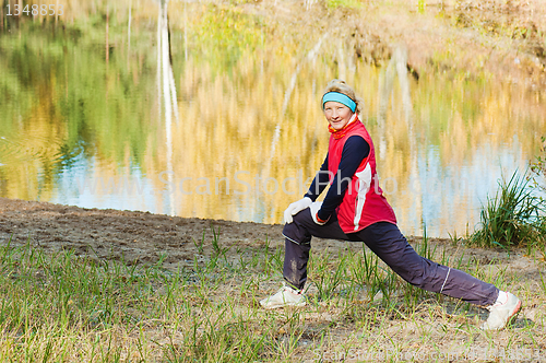 Image of The woman does sports exercises in autumn park