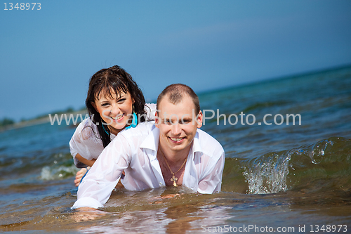 Image of Enamored man and girl lying in waves of sandy beach