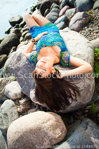 Image of beautiful brunette girl lying on beach stones