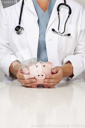 Image of Doctor with Caring Hands on a Piggy Bank
