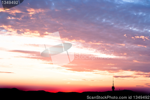 Image of Evening scene of an urban area with red clouds and silhouettes o