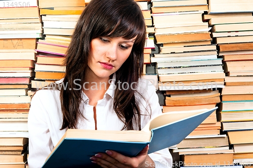 Image of Beautiful young student girl reading from a big book