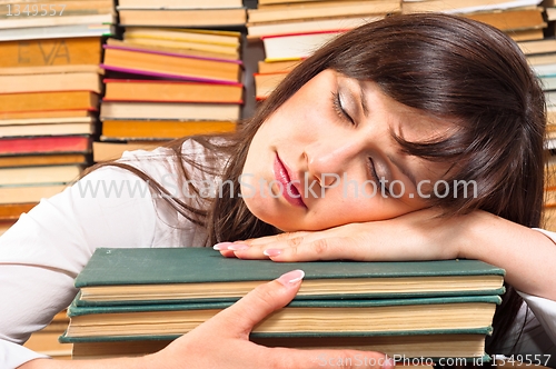 Image of Overworked university student sleeping on her books