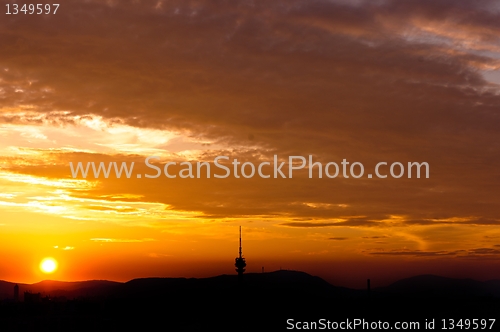 Image of Evening scene of an urban area with red clouds and silhouettes o