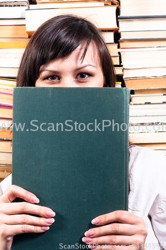 Image of Student girl hiding behind big book