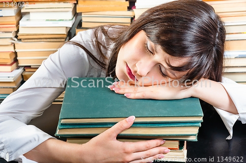 Image of Young university student sleeping on books