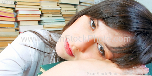 Image of Beautiful young student girl almost asleep on her books