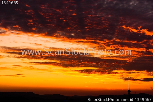 Image of Evening scene of an urban area with red clouds and silhouettes o