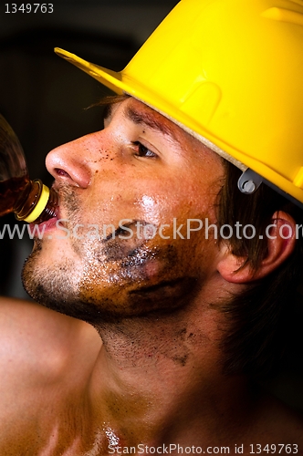 Image of Industrial worker with oil on his face drinking after job