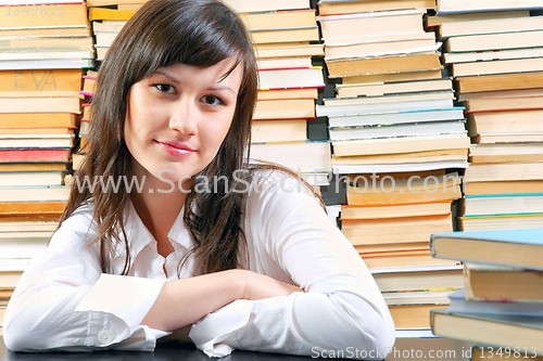 Image of Young school girl with a lot of books against her