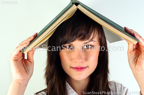 Image of Beautiful young girl hiding under book