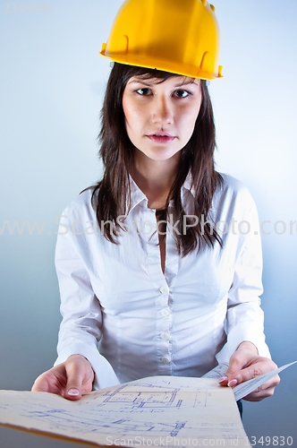 Image of Engineer woman in yellow helmet with plans